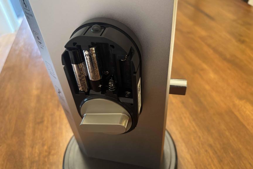 A smart lock shows indoor section with batteries partially installed.